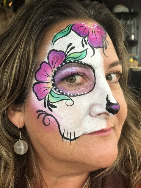 Tracy Nicholson, from Face Painting 4 You Hull, created this beautifully scary sugar skull. The chunky glitter and lacy linework gives an antique effect. Look in resale shops for costume pieces like hats, scarves, fake flower wreathes and more to match your sugar skull face paint design. SUGAR SKULL FACE AND CHEST PAINTING